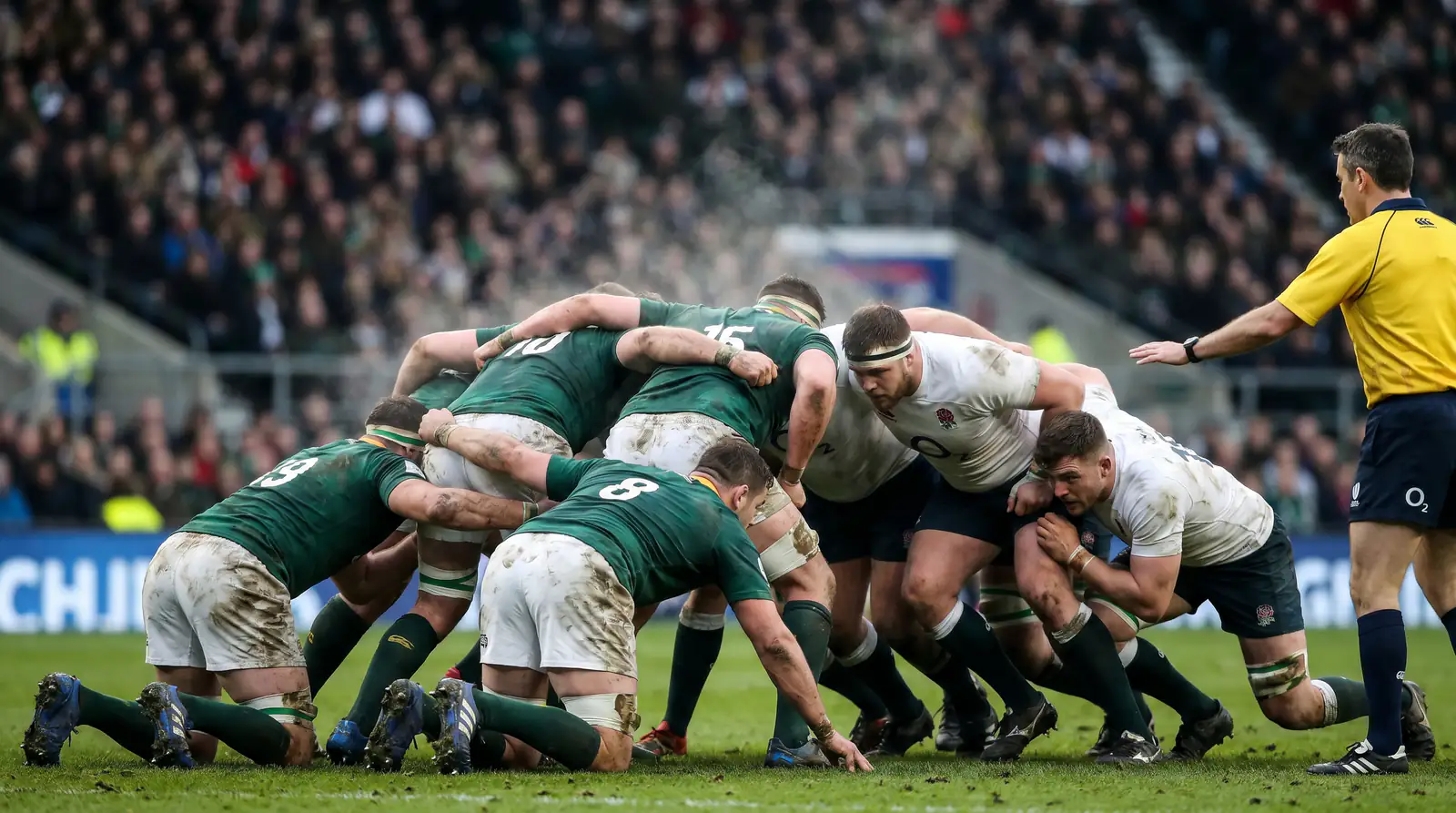 Rugby union forwards locked in a contested scrum on a grass pitch