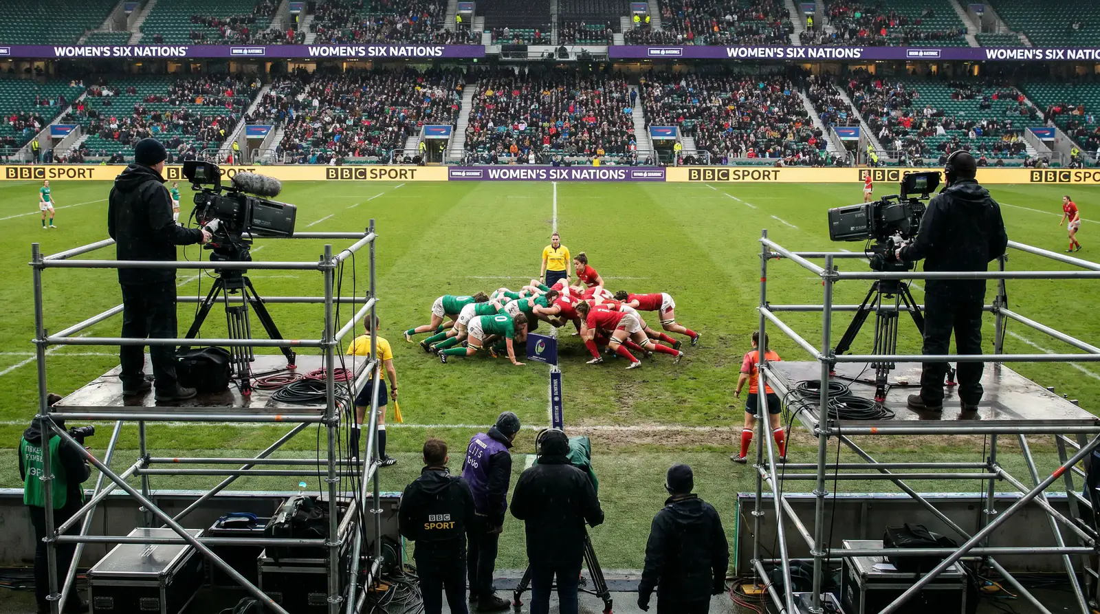 Television broadcast cameras set up at a women's rugby match with production crew